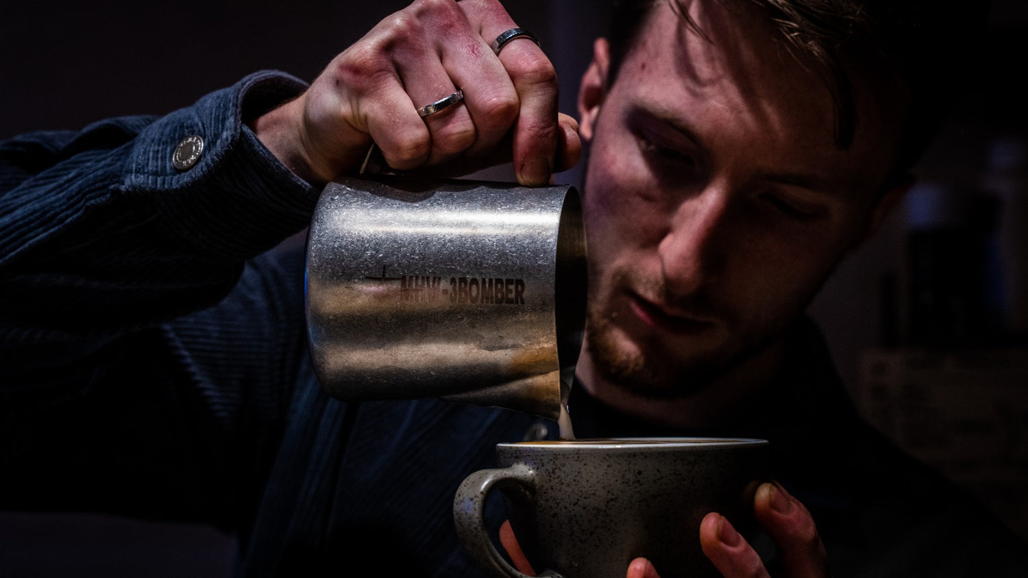 man holding milk pitcher pouring a coffee